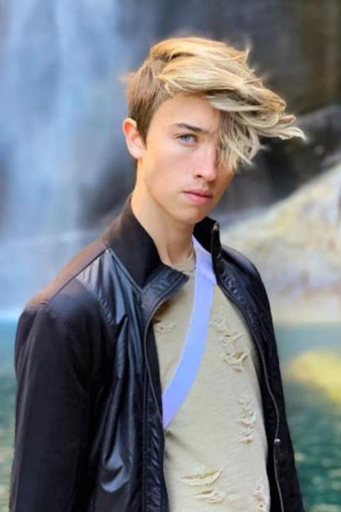 Maverick Baker in light grey tshirt and black jacket at waterfall