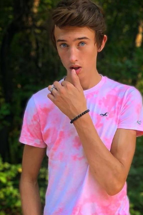 Maverick Baker in light pink tshirt and bracelet in hand