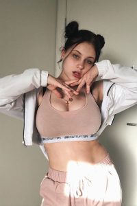 Hayley Stewart wearing brownish top and pajama and has twin tails. She is looks beautiful with her green eyes