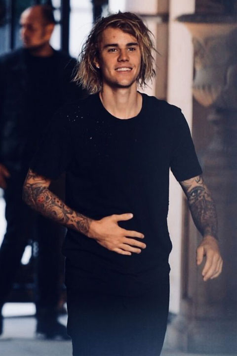 Justin Bieber is giving smile and wearing full black dress