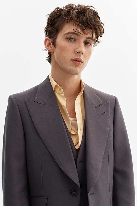 Troye Sivan in cream color shirt and grey coat