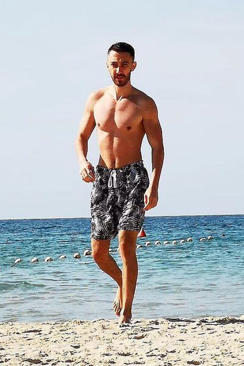 Michael Nicolae on beach in black and grey shorts