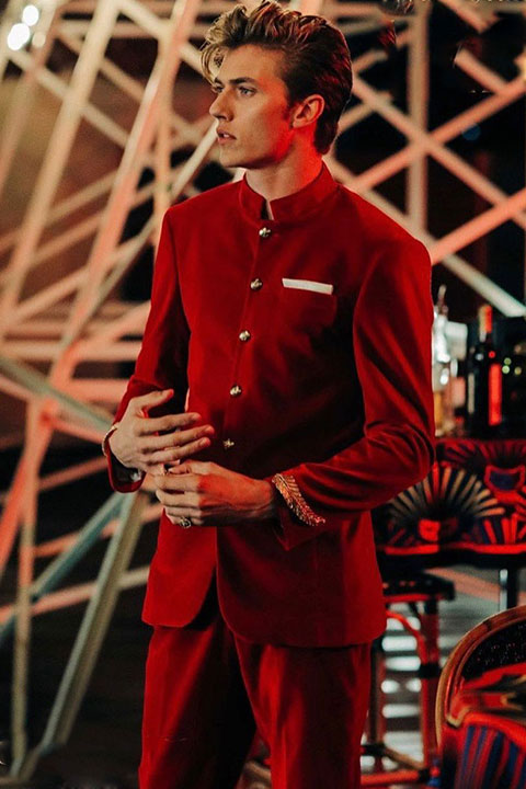 Lucky Blue Smith is looking awesome in red pent coat and posing for a picture beautifully.