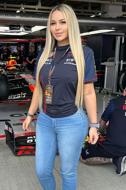 Andrea Abeli is posing beautifully in front of sports car.